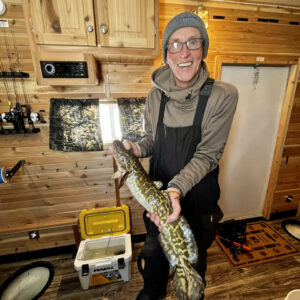 man ice fishing in ice house in minnesota