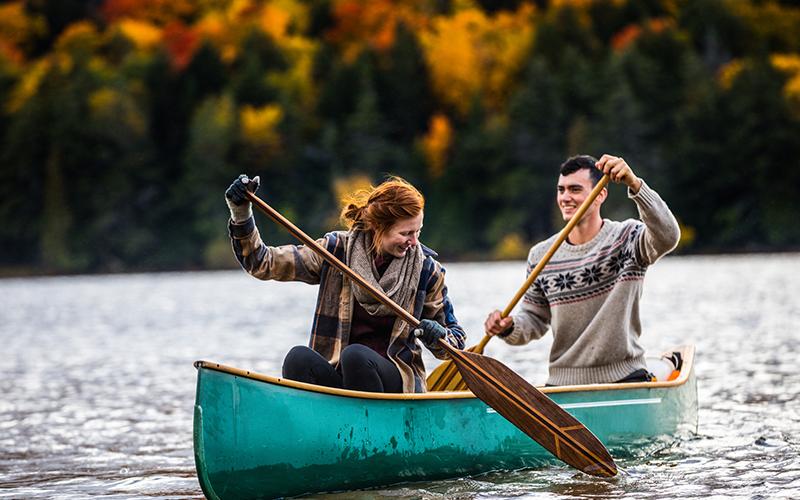 man and woman canoeing on an open lake
