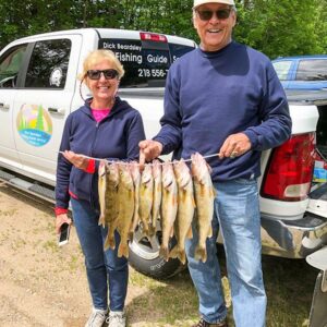 man and woman holding a line of fish next to dick beardsley guide service truck