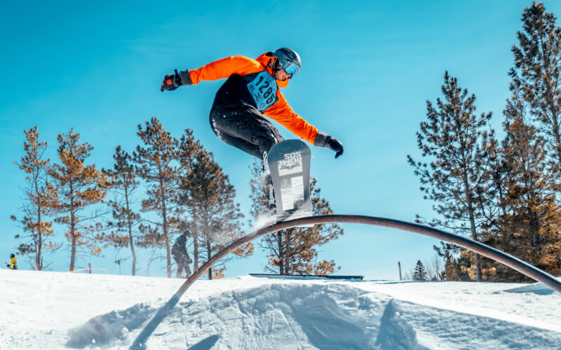 person snowboarding on rail in the snow