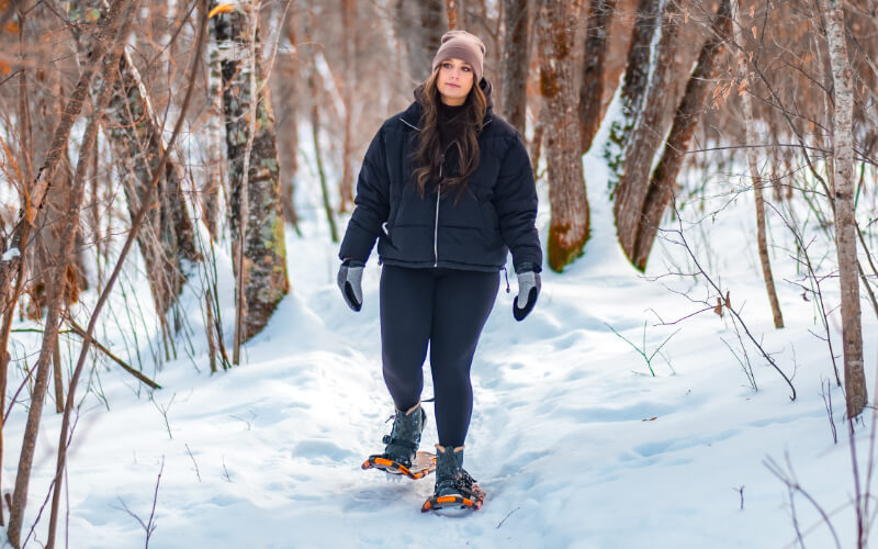 woman snowshoeing through the snow covered woods