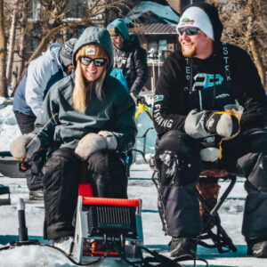 man and woman ice fishing on frozen lake in minnesota